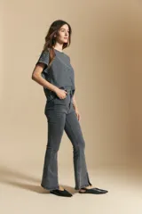 Jean oxford de tiro alto confeccionado en denim con spandex, de color gris oscuro lavado. Presenta un corte ajustado en la parte superior que se ensancha hacia el ruedo, el cual incluye aberturas frontales.