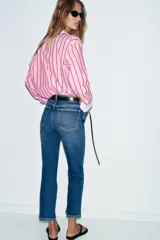 Jeans de tiro alto con corte mini flare y largo tobillero. Presentan diseño de cinco bolsillos, pernera estrecha con acabado evasé y cierre frontal con cremallera y botón.