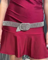 Cinturón de metal plateado cubierto de strass brillante, con hebilla rectangular decorada con pedrería y punta en forma de triángulo.