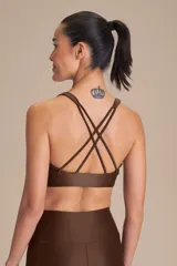 Top deportivo de compresión media con diseño de espalda cruzada y breteles finos. Confeccionado en tejido acanalado con un acabado de brillo sutil, cuenta con copas removibles y tecnología de ajuste adaptable.