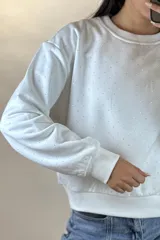 Buzo de cuello redondo y manga larga, color negro, con diseño de pequeños puntos brillantes distribuidos por toda la prenda. Presenta puños y ruedo acanalados.