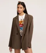 Blazer de mujer color marrón, de corte sastre alargado, con solapa ancha, cierre de doble botonadura y bolsillos tipo cuchillo.