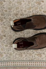 Bota tipo chelsea de punta redonda, confeccionada en una combinación de cuero texturizado y gamuza en tonos marrones. Presenta elásticos laterales negros y una suela track robusta de goma negra.