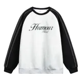 Buzo oversize de corte holgado, color gris melange en el cuerpo con mangas raglán en contraste color negro. Presenta cuello redondo, puños y cintura elastizados, costuras blancas decorativas a lo largo de las mangas y un estampado frontal con la palabra 'Humour' de efecto esfumado.