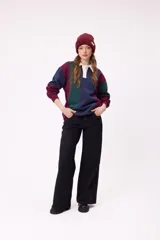 Gorro tipo beanie de punto acanalado color bordó, con etiqueta rectangular blanca con logo de la marca en el frente.