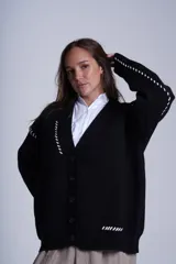 Cárdigan color beige con botones negros, escote en V y detalles de costuras bordadas en negro.