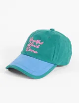Gorra de algodón color verde con visera celeste y bordado frontal con la frase 'Breakfast Lunch Dinner' en rosa.