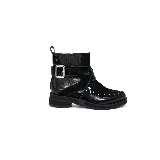 Bota corta de cuero y gamuza color negro, con taco bajo y suela plana. Presenta una correa lateral de cuero charolado con hebilla metálica, tachas decorativas en la puntera y paneles elásticos en los laterales de la caña.
