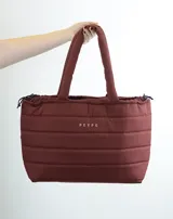 Bolso tipo tote bag acolchado color bordó, con asas de hombro tubulares y logo estampado en el frente.