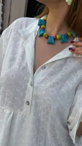 Vestido corto blanco con bordado calado, corte holgado, cuello camisero y mangas 3/4 con volados.