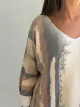 Sweater de punto con diseño abstracto de rayas verticales en tonos gris, beige y terracota. Presenta cuello en V, corte holgado y mangas largas con puños vueltos.