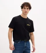 Remera masculina negra de algodón, corte comfort, con cuello redondo y mangas cortas. Presenta una estampa lettering con follaje "Royal Palace" en amarillo en el frente y la espalda.