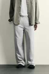 Pantalón jogger de corte relajado y pernera ancha, confeccionado en tejido de algodón con interior perchado. Cuenta con cintura elástica ajustable mediante cordón interior, bolsillos laterales y un bolsillo trasero de plastrón.