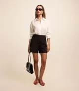 Short de sastrería negro, tiro alto, con cierre frontal de botones visibles.