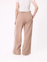 Pantalón de jogging Rusty modelo Delinez, color taupe, con cintura elástica y cordón ajustable. Presenta diseño de pernera ancha con tira lateral en contraste.