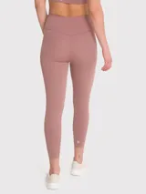 Calza deportiva de tiro alto con largo hasta el tobillo, confeccionada en tejido elástico de color rosado tierra. Presenta un diseño minimalista sin bolsillos y un pequeño logo bordado en la cadera.