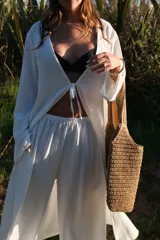 Pantalón de corte amplio y tiro medio, confeccionado en tela crepe color beige, con diseño fluido y holgado.