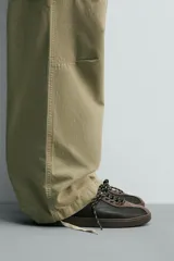 Zapatilla deportiva de estilo retro, confeccionada en una combinación de piezas de cuero texturizado y gamuza en tonos marrones. Presenta un diseño de doble cordonera con cordones claros y suela de goma a tono.