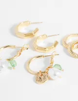 Set de aros dorados con diferentes diseños: aros tipo argolla con textura, aros tipo argolla con dijes de perlas y cuentas verdes, y aros tipo argolla hexagonales.