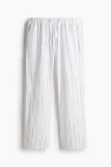 Pantalón de corte relajado confeccionado en algodón, con diseño a rayas verticales. Presenta cintura elástica con cordón de ajuste, cierre decorativo y bolsillos laterales.