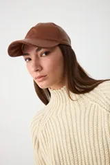 Gorra con visera confeccionada en cuero color tostado, con diseño clásico de seis paneles y cierre ajustable en la parte posterior.