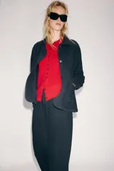Chaqueta oversize de mezclilla color azul marino, de cuello solapa y manga larga, con bolsillos de parche en el delantero y cierre frontal con botones metálicos.