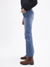Jean de corte bootcut en color azul medio, con diseño de cinco bolsillos, cierre frontal con botón y cremallera, y bajo con terminación al corte.