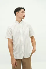 Camisa de manga corta confeccionada en lino y algodón, con fit regular y logo bordado. Color beige con rayas verticales blancas.