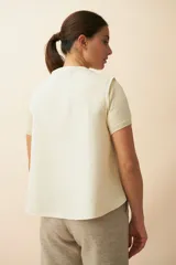 Chaleco color beige con textura tipo espiga, corte holgado y solapa cruzada.