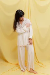 Conjunto de dos piezas compuesto por camisa oversize de manga larga con botones frontales y bolsillo en el pecho, y pantalón de corte amplio con cintura elástica. Presenta un diseño fluido y liviano con textura sutil.