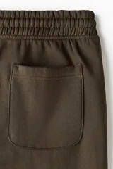 Pantalón deportivo de felpa en mezcla de algodón con interior cepillado. Presenta cintura elástica con cordón de ajuste, bolsillos laterales y puños acanalados en los tobillos.