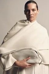 Bolso alargado de piel color blanco hueso, con asa de hombro y cierre de cremallera.