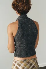 Top de punto jaspeado en color gris oscuro, con cuello alto y diseño halter sin mangas. Confeccionado con una mezcla que incluye lana, presenta terminaciones acanaladas en el cuello y el ruedo.