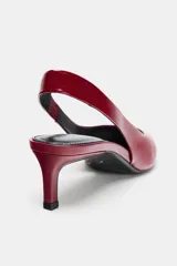 Zapato destalonado de piel color rojo brillante, con punta fina y tacón kitten. Posee una tira trasera elástica para ajuste.