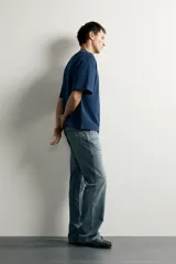 Jeans flare fit de denim rígido en color azul con efecto lavado. Presentan tiro medio, diseño de cinco bolsillos y cierre frontal con cremallera y botón.
