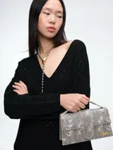 Sweater de punto gris con escote en V profundo, hombros caídos y mangas largas. Presenta un diseño de calce relajado con sutiles micro lentejuelas integradas en el tejido.