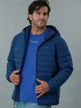 Campera acolchada con capucha, color azul, con cierre frontal y bolsillos laterales con cremallera. Presenta el logo de Calvin Klein en el pecho.