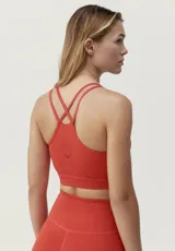 Top deportivo de sujeción media-alta, confeccionado en tejido técnico transpirable con perforaciones láser en la espalda.