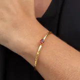 Brazalete ajustable de plata 925 bañada en oro 18k con una piedra granate central en forma de gota.