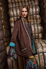 Blazer holgado de terciopelo marrón con cuello con solapa, sin cierre frontal y con tres bolsillos funcionales. Intervenido artesanalmente con detalles de tientos y pompones de algodón teñidos a mano. Forrado en las mangas con estampa the farra.