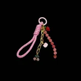 Colgante para cartera con cadena dorada y charms colgantes: frutilla roja, Hello Kitty rosa, cerezas con strass y cordón trenzado rosa.