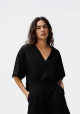 Blusa negra de manga corta, con escote pronunciado en V y corte holgado.