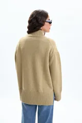 Polera de punto en color verde, con cuello alto, mangas largas con puños acanalados y aberturas laterales en el ruedo.