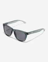 Lentes de sol Hawkers modelo One Raw con armazón de policarbonato transparente en tono gris oscuro y cristales oscuros.