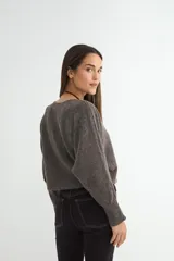 Sweater de punto negro, de corte holgado y diseño cropped, con cuello redondo y mangas largas.