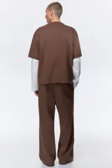 Pantalón deportivo de felpa marrón con elástico en la cintura, cordón de ajuste y bolsillos laterales, corte holgado.