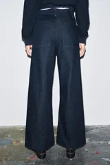 Jeans de tiro alto, pierna ancha y largo al tobillo, en denim celeste claro con efecto lavado. Presenta costura marcada en el centro de cada pierna y cierre frontal con cremallera y botón.