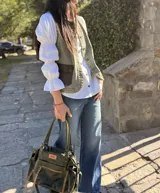 Chaleco de jean con efecto lavado, cierre frontal con botones metálicos y dos bolsillos cargo delanteros de cuero negro.