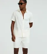 Bermuda de hombre Marfinno confeccionada en tejido texturizado con patrón vertical, color blanco, de corte recto, con cintura elástica y bolsillos.