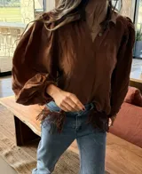 Camisa de manga larga abullonada color marrón, con cuello camisero, escote en V con botones y puños elásticos.